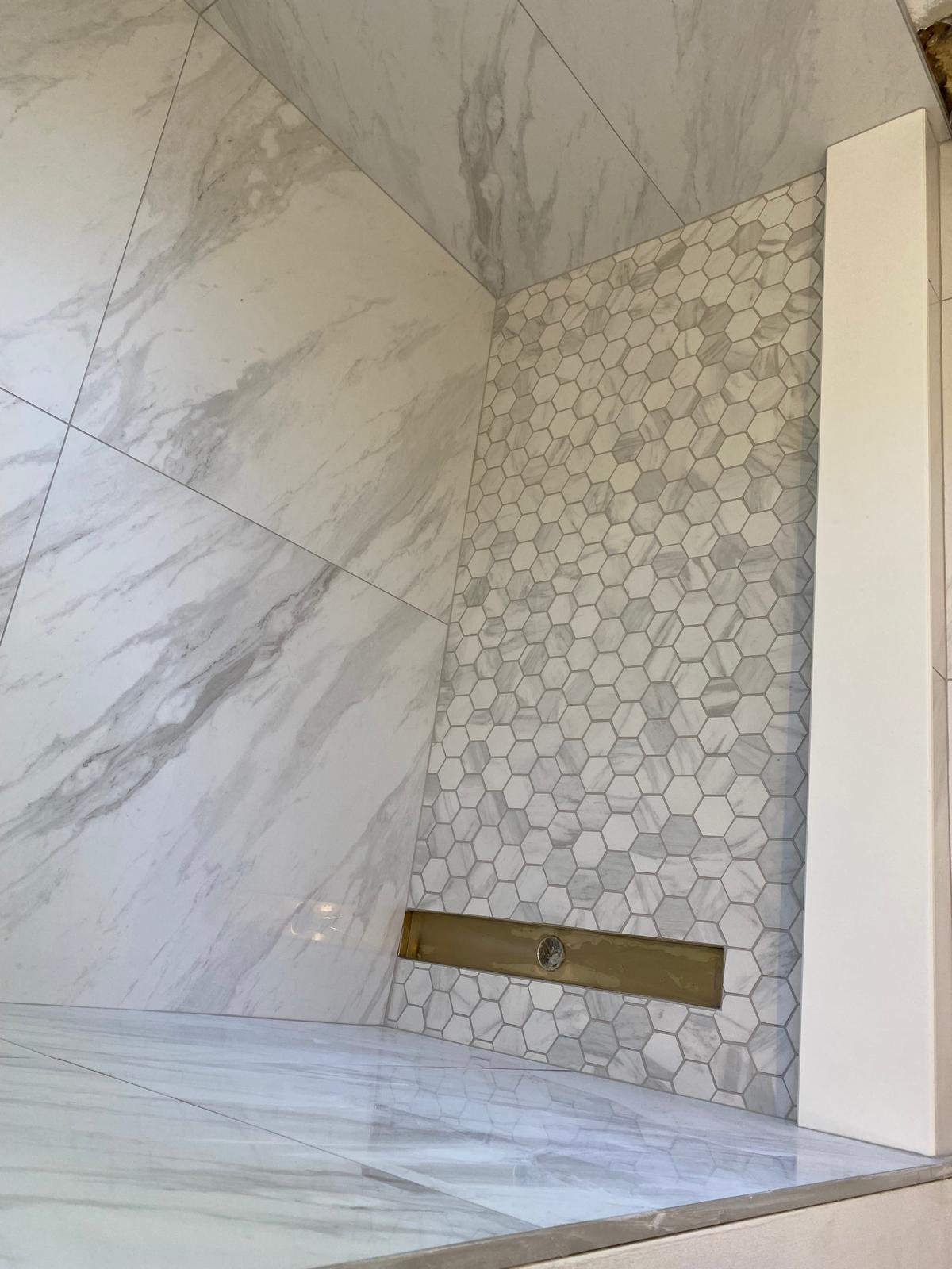 Custom shower wall with hexagonal mosaic tile detail by Souza Installation