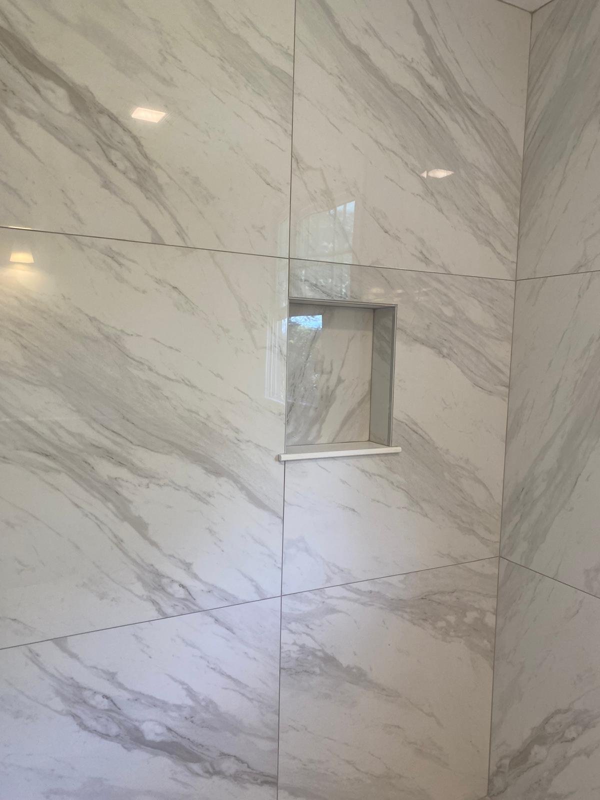 Recessed shower niche surrounded by marble-look tile by Souza Installation