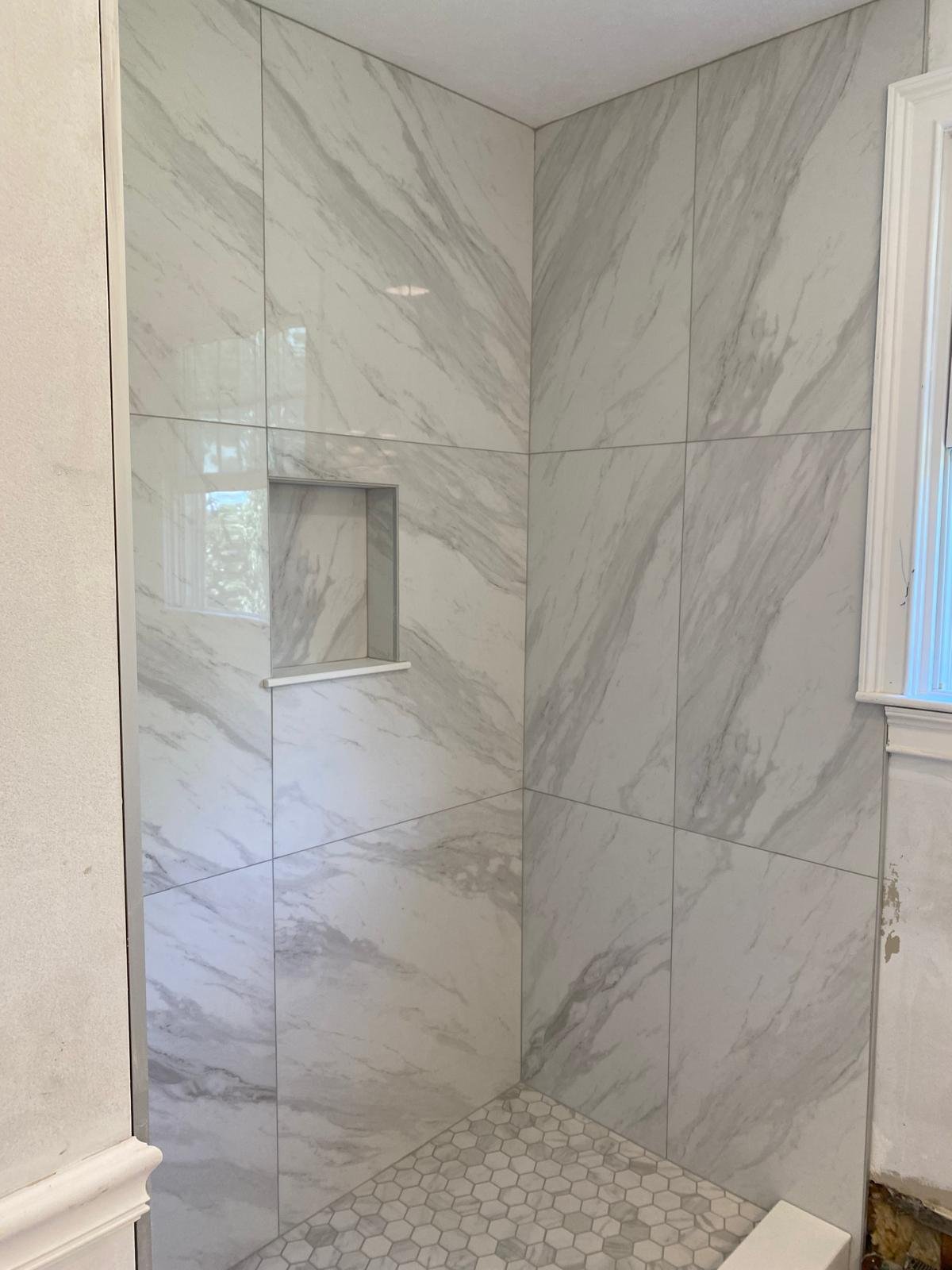 Large-format marble-look shower tile installation by Souza Installation